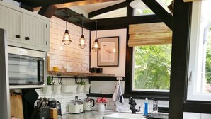 Una cocina con armarios blancos, piso a cuadros y sillas de madera.