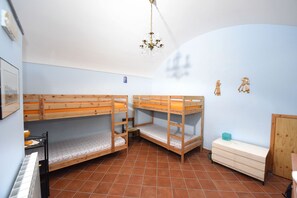 Una stanza con letti a castello, una cassettiera e un lampadario.