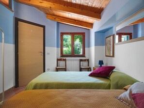 A bedroom with a bed, a window, a chair, a lamp, and a door.