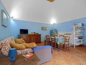 Una sala de estar con sofá, televisión y comedor con sillas y una mesa.