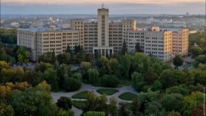 A large, multi-story building with a central tower, surrounded by a well-maintained park with various trees and pathways. - Apartments Levada  (Kharkiv)