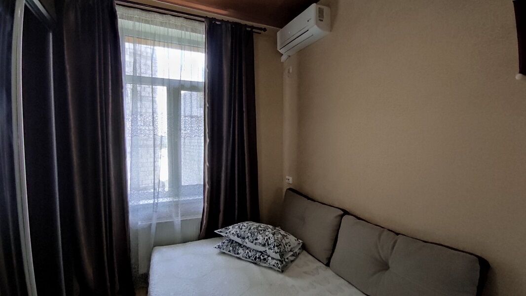 Un dormitorio con cama, ventana con cortinas y un equipo de aire acondicionado en la pared.