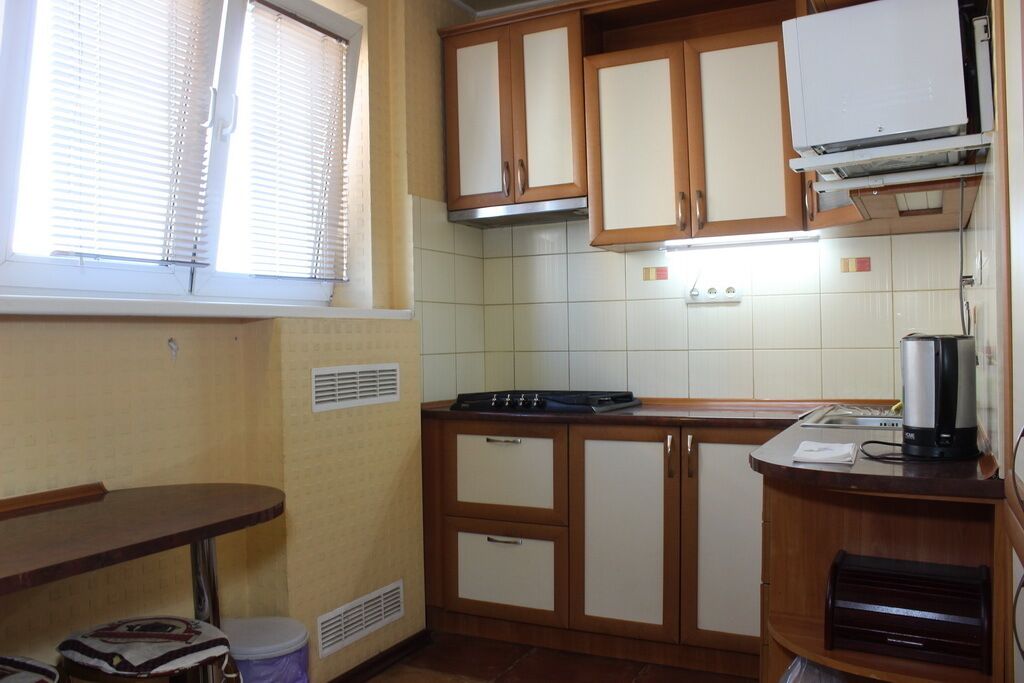 A compact kitchen with wooden cabinets, a built-in stove, and a coffee maker.