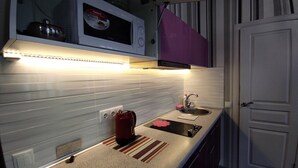 A compact kitchen with a microwave, kettle, and sink. - Apartments Levada  (Kharkiv)