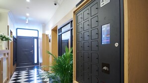 Un pasillo con piso a cuadros, una recepción y un moderno ascensor con pantalla digital.