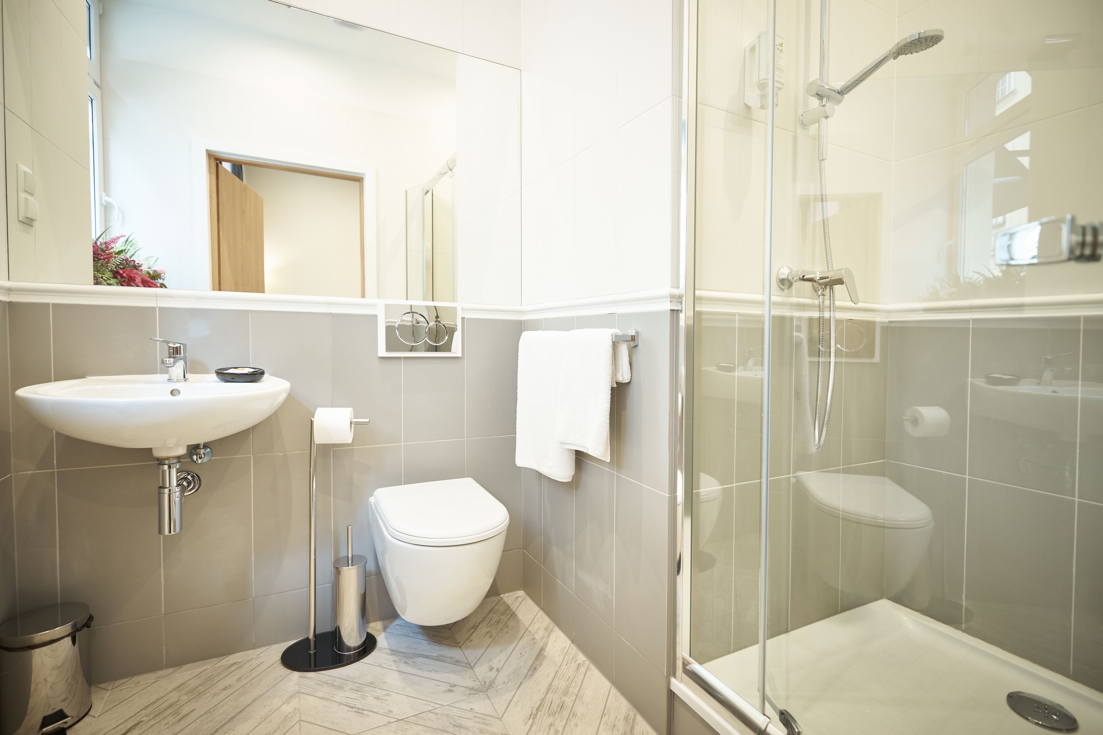 Et moderne badeværelse med vask, toilet og brusekabine med glasvægge.