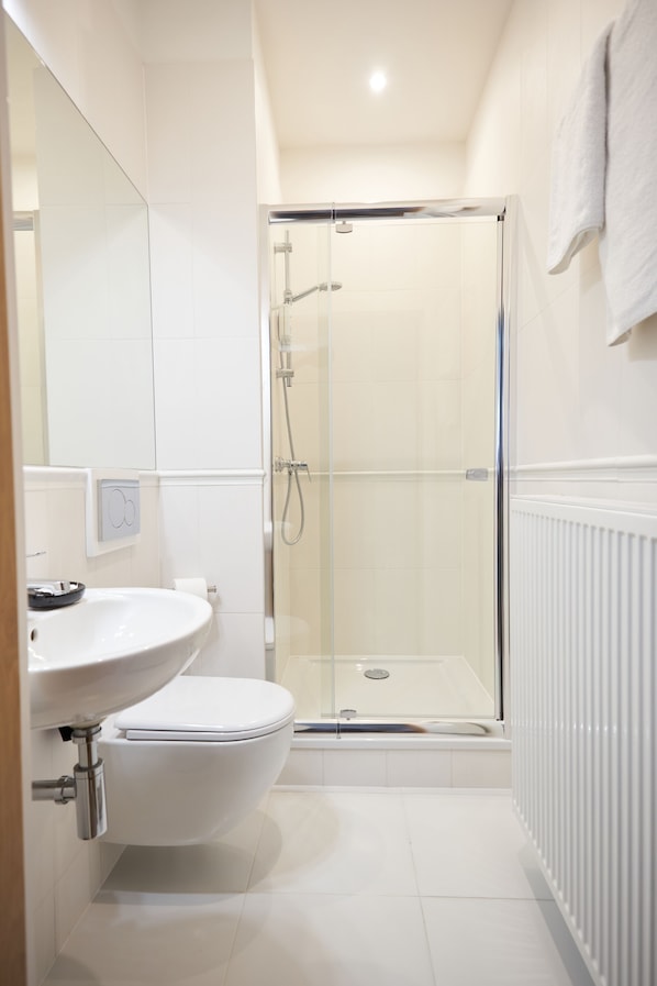 Une salle de bain moderne avec une douche à parois de verre, un lavabo blanc et des toilettes.