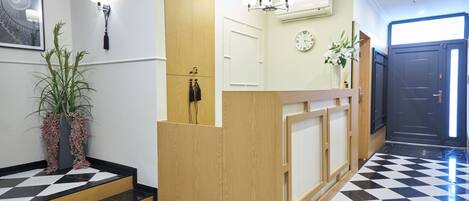 A reception area with a check-in counter, a clock, a staircase, and a potted plant.