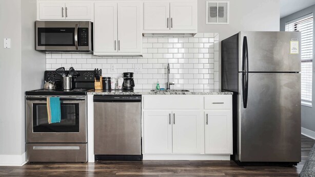 A modern kitchen with white cabinets, stainless steel appliances, and a tiled backsplash. - Walk to Nightlife & Attractions (Indianapolis)