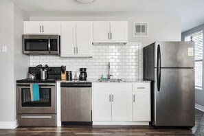 Een moderne keuken met witte kasten, roestvrijstalen apparatuur en een betegelde achterwand.