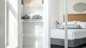A bedroom with a bed, a bedside table, a mirror, and a closet with shelves. - Walk to Nightlife & Attractions (Indianapolis)