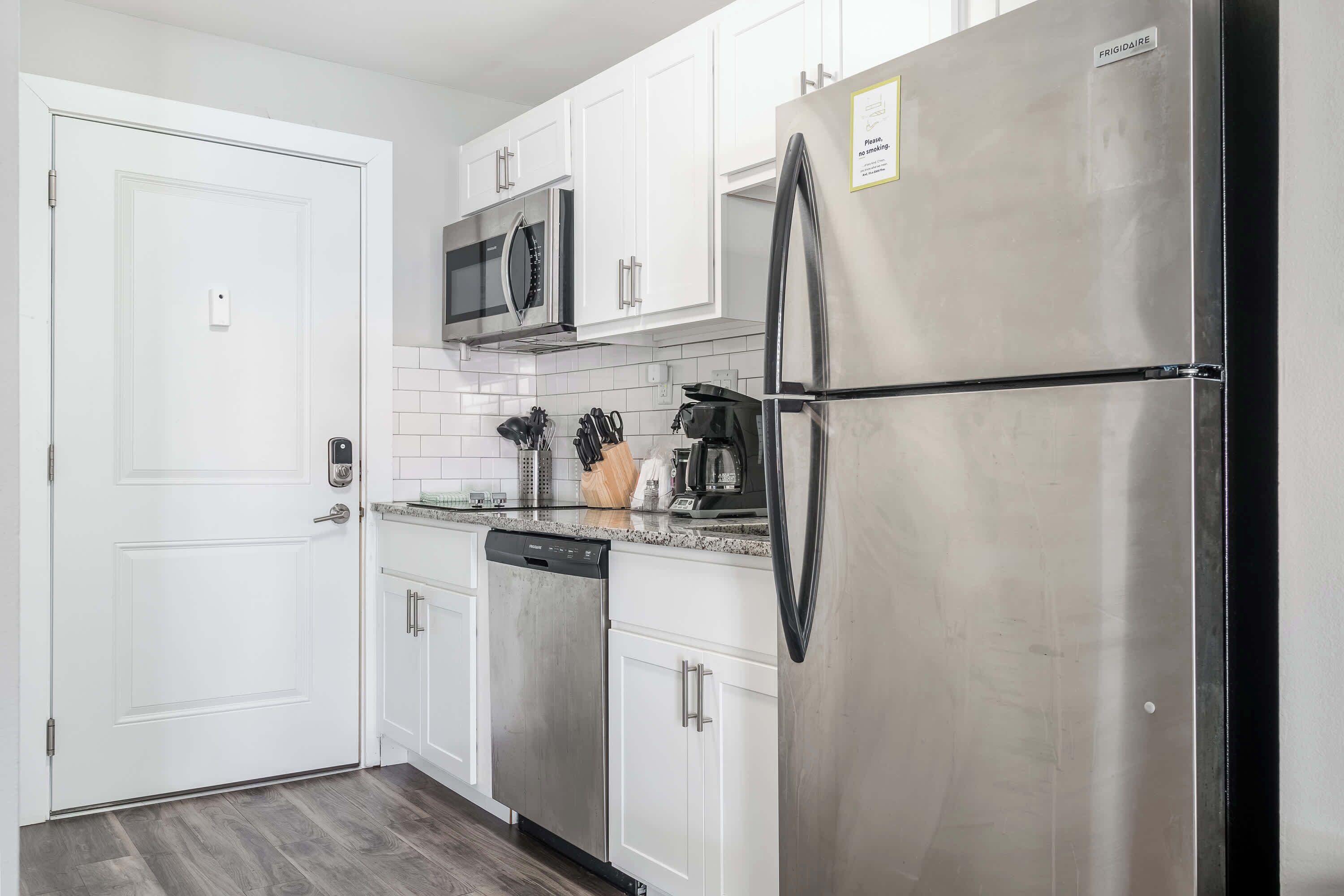A modern kitchen with white cabinets, stainless steel appliances, and a black refrigerator.