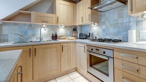 Una cocina moderna con armarios de madera, una campana extractora de acero inoxidable, horno empotrado y salpicadero de azulejos.
