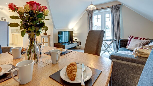 Una sala de estar acogedora con comedor, televisor y ventana con cortinas.