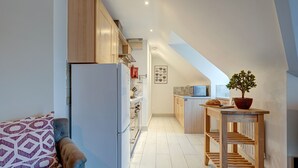 Una cocina moderna con armarios de madera, horno integrado y una mesa de madera con planta en maceta.