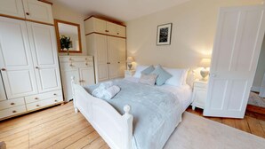 A bedroom with a bed, white wardrobe, bedside tables, and a framed picture on the wall. - Abbey Road | Oxford Holiday Let | 2 Beds & Sleeps 3 (Oxford)