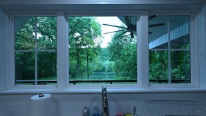 A kitchen with a window view of a forest and a ceiling fan. - Top Location! 3D & Video Tour. Riverside 4/3 w/ the best water access & privacy! (Flippin)