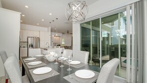 Een moderne eetkamer met een donker houten tafel voor zes personen, witte stoelen en een bijzondere kroonluchter.