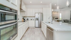 Een moderne keuken met witte kasten, een roestvrijstalen koelkast en een inbouwoven.