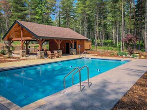 Une cabane en bois avec une piscine, entourée d’arbres.
