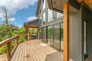 Une terrasse en bois avec des portes vitrées donnant sur un espace extérieur abrité.