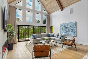 A spacious living room with a large sectional sofa, a coffee table, a leather armchair, and a painting on the wall.