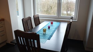 A dining area with a table, chairs, and a window with a view of trees. - Nice, centrally located apartments in Cologne, streetcar stop in front of the door. (Köln)