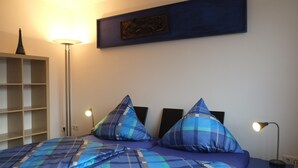 A bedroom with a bed, two bedside lamps, a wall-mounted artwork, and a floor lamp. - Nice, centrally located apartments in Cologne, streetcar stop in front of the door. (Köln)