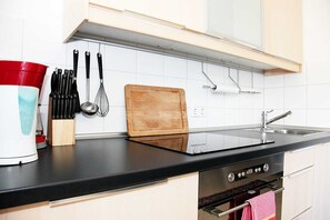A kitchen with a black countertop, white tiles, a wooden cutting board, and a red and white appliance. - Comfortable apartments in a great location in the center of Cologne, with a tram stop right outside the door. (Köln)