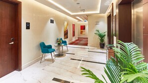 Un vestíbulo de hotel con suelo de mármol, puertas de madera y una recepción con sillas.