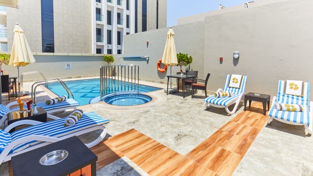 Zona de piscina en la azotea con sillones de descanso, sombrillas y una parrilla.