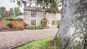 A stone building with a traditional design, a gravel driveway, and a tree with moss. - The Bladon Farmhouse | Oxfordshire Holiday Let | 2 Beds & Sleeps 5 (Bladon)