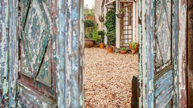 A rustic wooden door leading to a garden area with potted plants and a small wooden structure. - The Bladon Farmhouse | Oxfordshire Holiday Let | 2 Beds & Sleeps 5 (Bladon)