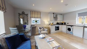 Eine moderne Wohnung mit Essbereich, Wohnzimmer mit Sofa, Küche mit Geräte und Waschbereich.