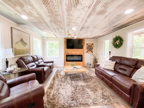 A living room with leather sofas, a fireplace, and a TV mounted on the wall.