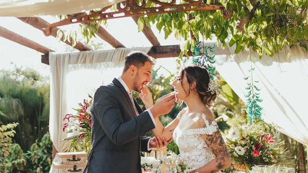 A couple under a pergola with a table of floral arrangements and vintage boxes. - Maria Barbosa Tiradentes Hotel and Spa (Tiradentes)