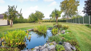 Ein Garten mit Teich, Pflanzen und Bäumen.
