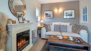 Ein Wohnzimmer mit Kamin, einer Couch, einem Couchtisch und Wandbildern.