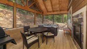 Une terrasse extérieure couverte, dotée d’un jacuzzi, de meubles en osier et d’une cheminée.