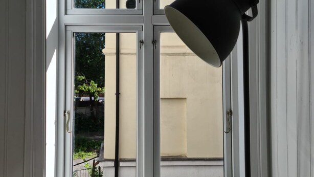 A room with a white-framed window, a black desk lamp, and a potted plant on the windowsill. - Oslo International Designers Space (Oslo)