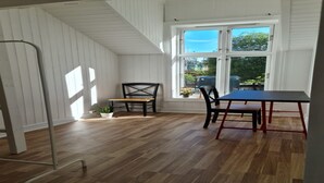 A room with a wooden floor, a table with chairs, a ladder, and a window with a view of the outside. - Oslo International Designers Space (Oslo)