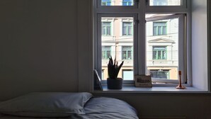 A bedroom with a bed, a window with a view of buildings, a potted plant, and a sign that says "ROME". - Oslo International Designers Space (Oslo)