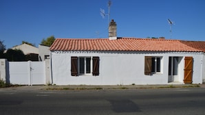A single-story building with a red-tiled roof, white walls, and two wooden doors.