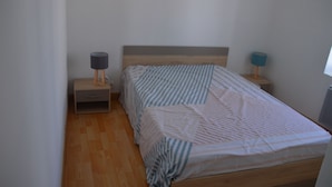 A bedroom with a wooden bed, two bedside tables, and a window.