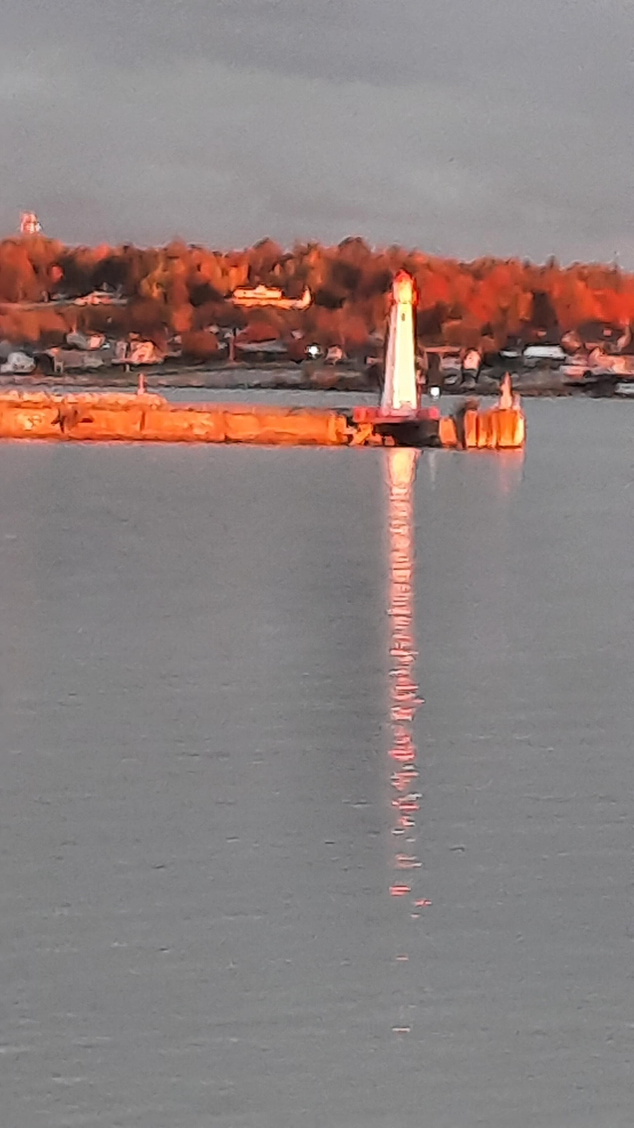 A lighthouse by a calm body of water with a clear reflection.
