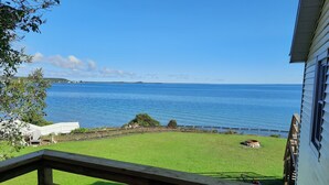 A view from a porch overlooking a grassy yard and a body of water. - Bayview #1 on Lake Huron (Saint Ignace)