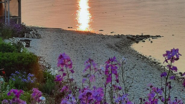 A sunset over a calm river with a statue in the foreground and a building on the left. - Bayview #1 on Lake Huron (Saint Ignace)