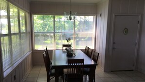 A dining room with a large table and chairs, a chandelier, and a door with a lock.