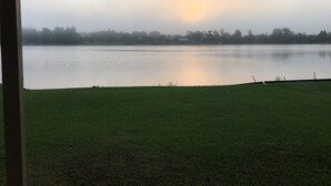 A view of a lake from a covered area with a grassy foreground.