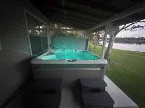 Un bain à remous doté d’une enceinte en verre, de deux repose-pieds et offrant une vue sur un lac.